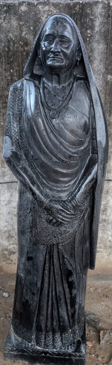Black granite statue of elderly lady in saree