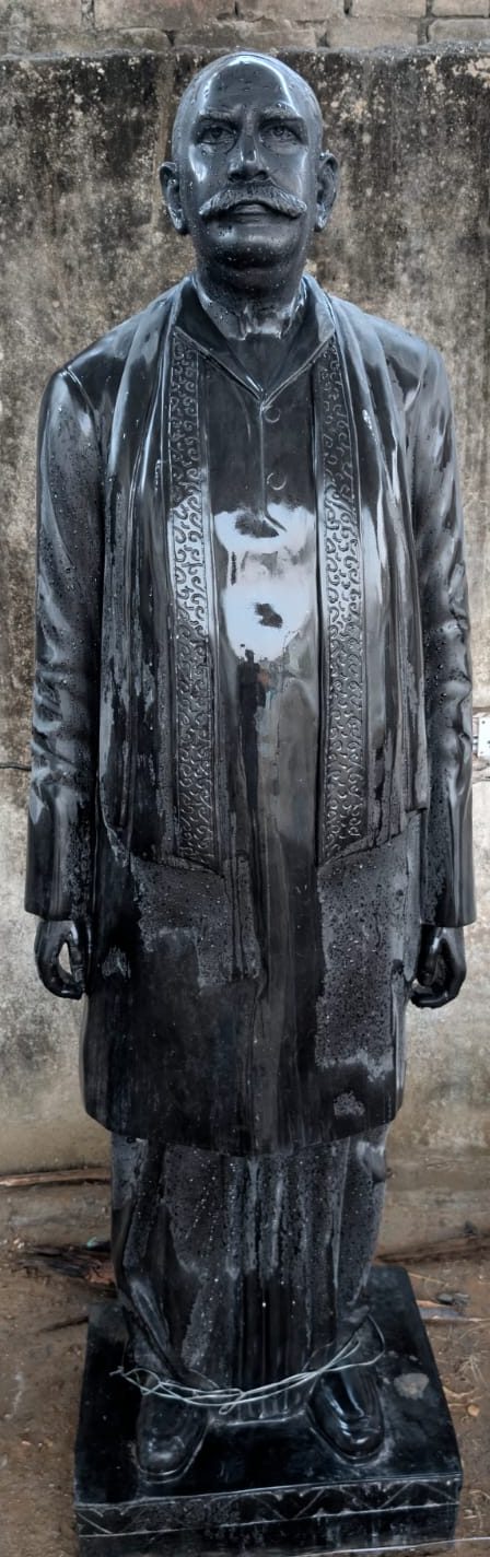 Black granite statue of gentleman in traditional attire